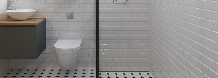 Ett badrum med vitt kakel på väggarna och svart/vitt klinker på golvet.