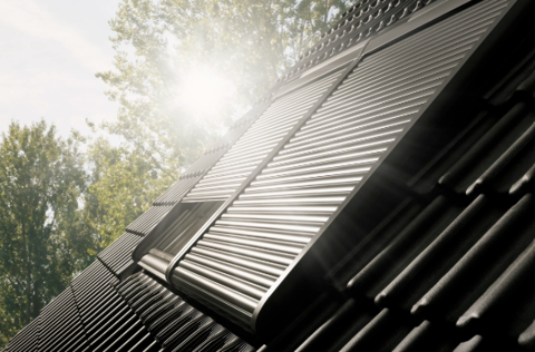 Vackert solsken mot ett takfönster med utvändig markis som är delvis öppen - Velux takfönster.