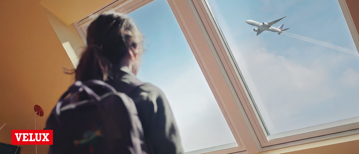 Velux takfönster och tjej som blickar upp mot himlen | Beijer Byggmaterial