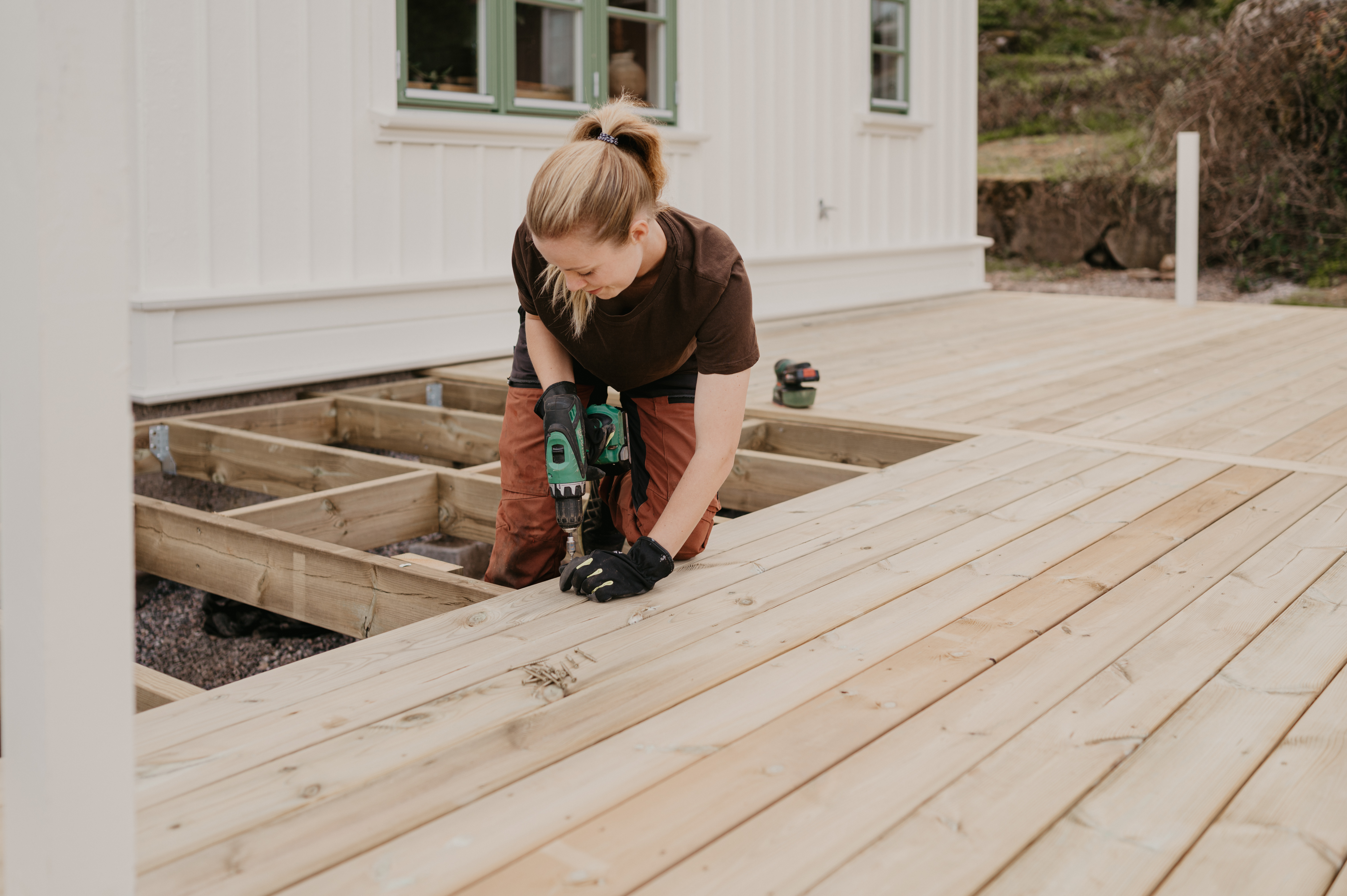 Här skruvar hon dit trallbrädor på det färdiga bjälklaget på altanen.