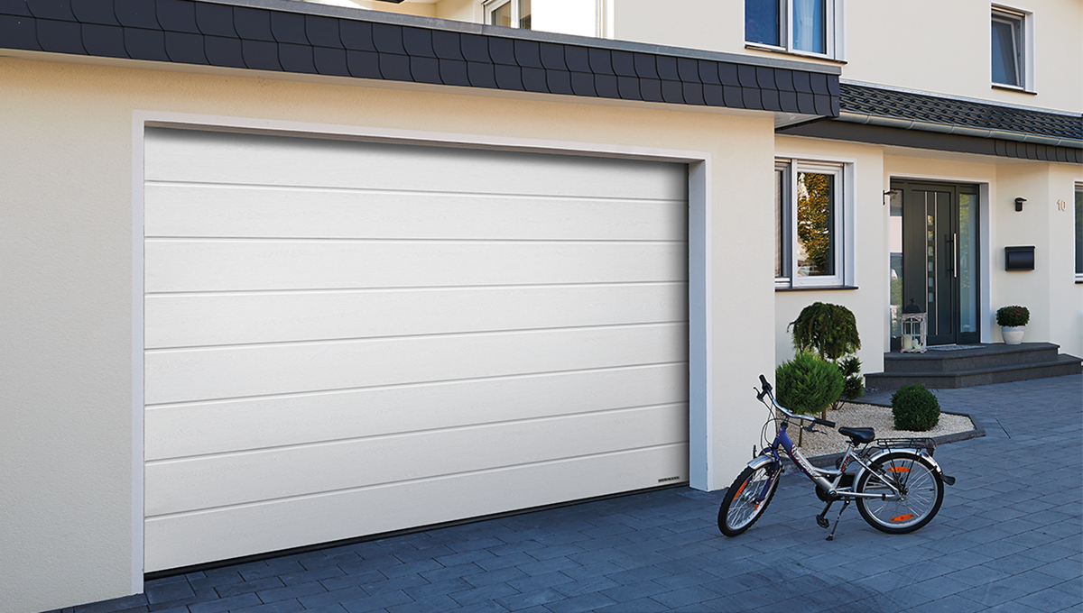 Vit garageport med en husfasad.