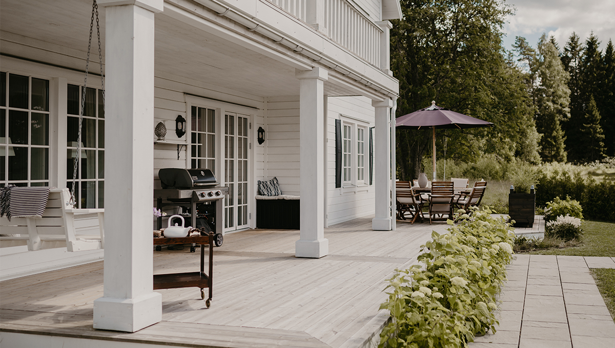 Nybyggd altan i trä vid en villa med gott om plats för utemöbler och sociala ytor.